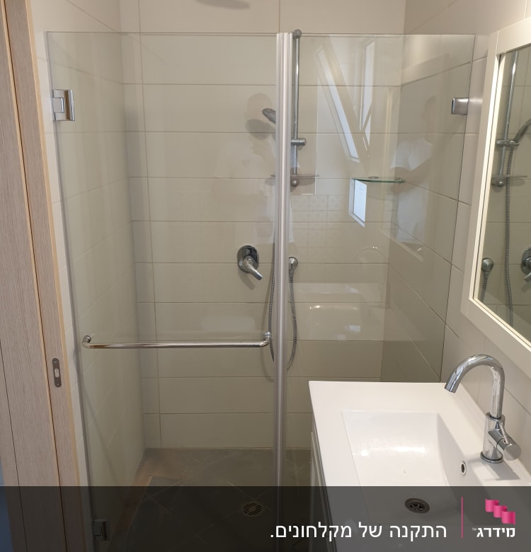 מקלחת עם דלת זכוכית, ראש מקלחת וברז.